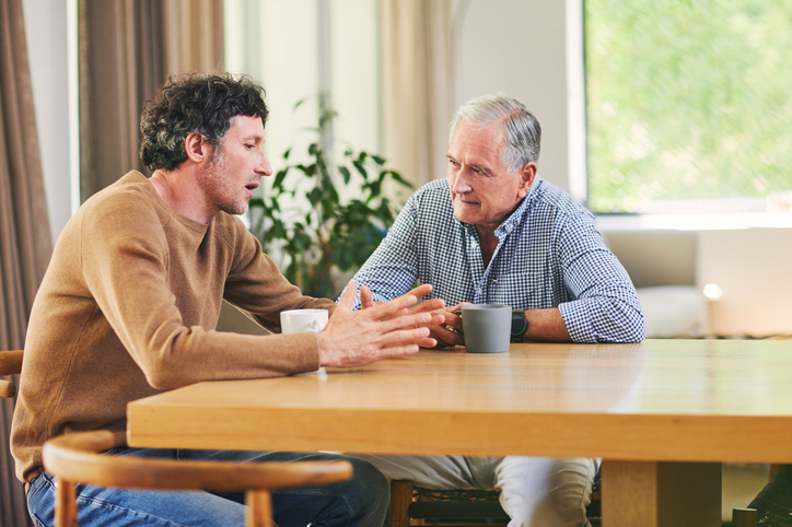 Senior man having a conversation with his adult son.